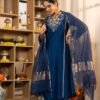 The pure Satori silk kurta is adorned with intricate machine embroidery and delicate handwork across the sleeves and neckline, lending a touch of regal finesse. It is paired with shantoon pants for effortless comfort and a flowing silhouette. Completing the ensemble is a statement pure zari stripe Banarasi silk dupatta, beautifully dyed to perfection, adding grandeur and festive charm